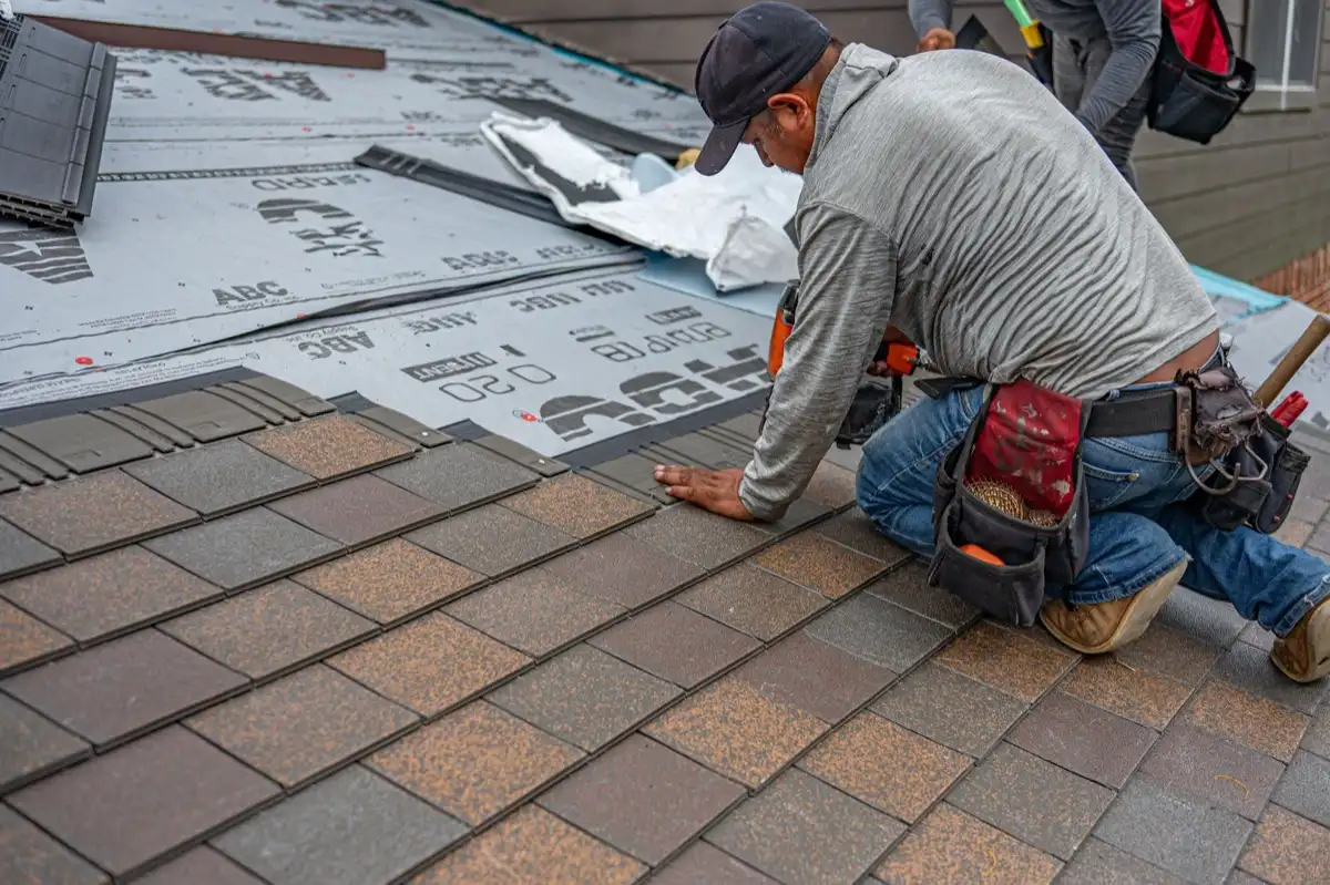Roofing installer fastening shingles over new underlayment in Downey, CA